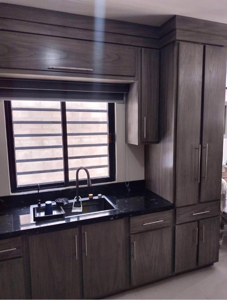 Cocina integral instalada en gris con cubierta oscura y tarja bajo ventana